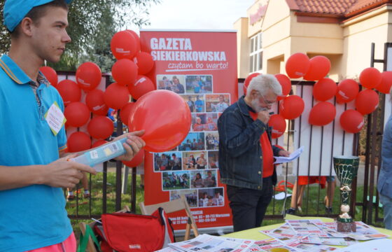 Stoisko promocyjne "Gazety Siekierkowskiej", na stole leżą egzemplarze gazety, stoisko jest udekorowane balonami i zdjęciami.