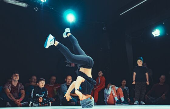 Chłopak na scenie - tańczy breakdance, na głowie. Za nim siedzą widzowie