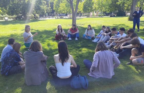 Grupa młodzieży siedzi w kręgu na trawie